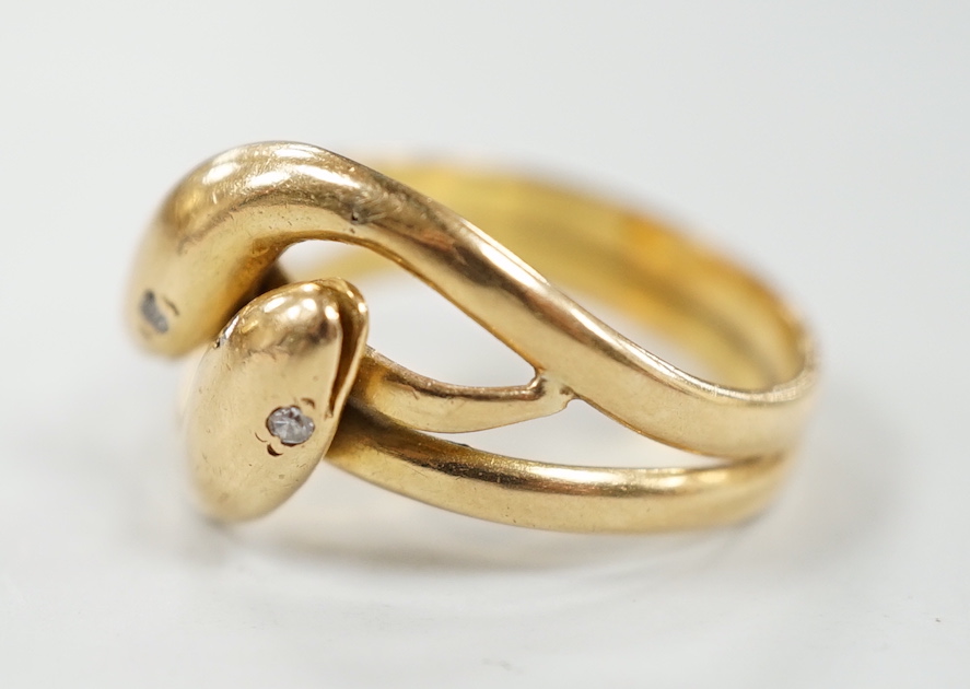 A yellow metal twin shank, two headed entwined serpent ring, with diamond chip set eyes size N/O, gross weight 6.2 grams.